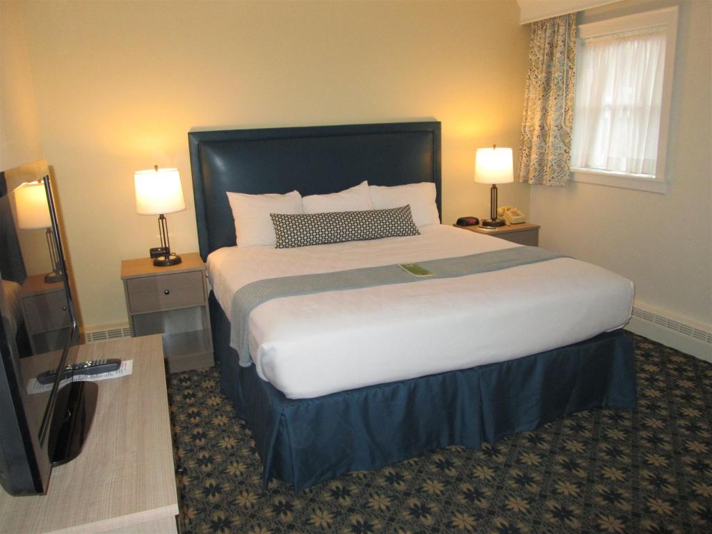 a room with a large bed with blue and white bedding. A TV sits on a console to the left.